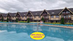 a large swimming pool in front of a large building at Bešeňová Apartment in Bešeňová