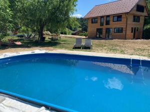 a large blue swimming pool in front of a house at Hillside Bio Glamping in Prebold