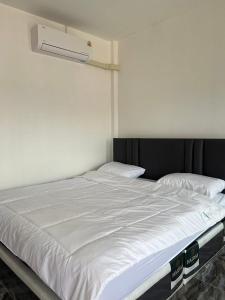 een groot wit bed in een witte kamer bij Saint Jira Hotel in Chum Phae