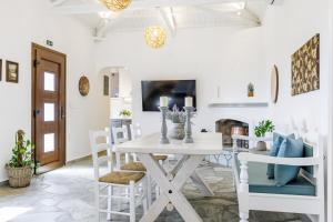 a white dining room with a white table and chairs at Bleu & Vert in Skopelos Town