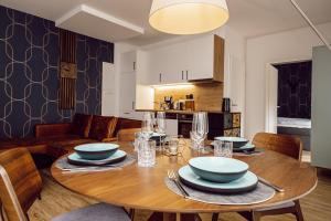 a dining room with a wooden table with plates and silverware at Alpenrausch 2 in Kiefersfelden