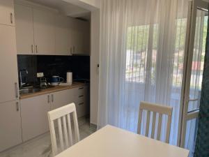 a kitchen with white cabinets and a table and chairs at Greystone House Apartments in Kovači