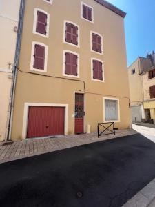 Un gran edificio amarillo con un garaje rojo. en Joli duplex plein centre, parking sur demande à la réservation, en Issoire