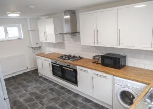 a kitchen with white cabinets and a stove top oven at City breaks Corby Double ensuites with tv in Rockingham +25 photos