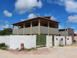 a building behind a white fence in front of a building at Refúgio do Mar in Beberibe
