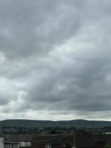 a kite flying in a cloudy sky over roofs at Oakbridge Studios in Burnley