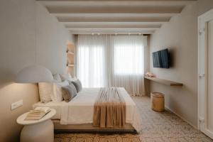 a white bedroom with a bed and a window at Castellum Suites in Naxos Chora