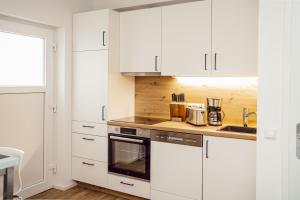 a white kitchen with white cabinets and a sink at Alpenrausch 3 in Kiefersfelden