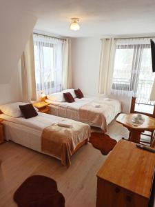 Un dormitorio con dos camas y una mesa y ventanas. en Stramówka, en Groń