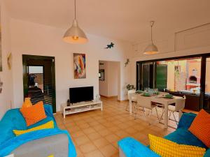 Una sala de estar con un sofá azul y un comedor. en Nur house villa and private pool, en La Oliva