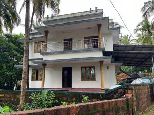 a white house with a balcony on top of it at Bekal Bliss Stay in Kotikulam