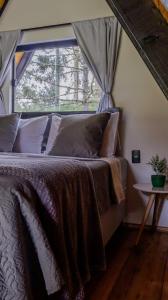 a bed in a room with a large window at Chalés Sol da Serra - Eucalipto in Rio Rufino