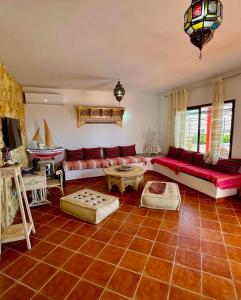 a living room with red couches and a table at Dar kerkwen in Bin Rhilouf