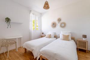 two beds in a bedroom with white walls and a chair at Appartement T4 centre-ville St Nazaire in Saint-Nazaire