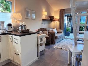 a kitchen with white cabinets and a living room at Ferienwohnung MALIBU S am See in Wettringen