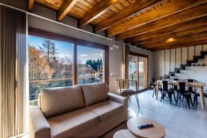 Una sala de estar con un sofá y una ventana grande. en CIERVO - Departamento céntrico, en Villa La Angostura