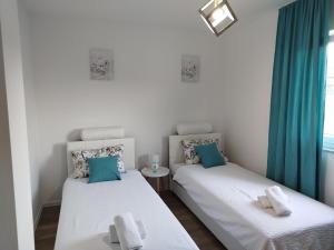 two beds in a room with blue curtains at Apartman David in Jajce