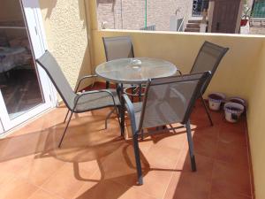 une table en verre et quatre chaises sur une terrasse couverte dans l'établissement Fiesta 165, à Mazarrón