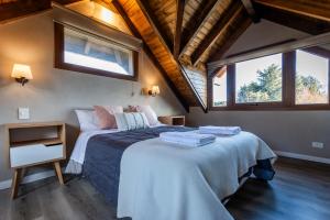 Un dormitorio con una cama y dos ventanas en CIERVO - Departamento céntrico, en Villa La Angostura