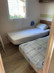 two beds in a room with a window at Camping 4 Étoiles Mobilhome Chez Jéjé et Fredo in Saint-Jean-de-Monts +4 photos