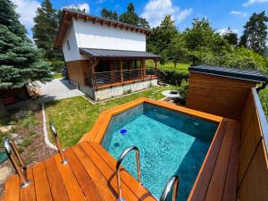 a pool with a wooden deck and a house at Chalet Slapy in Slapy