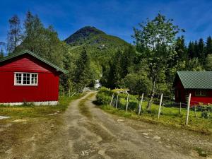 eine rote Scheune und eine unbefestigte Straße neben einem Berg in der Unterkunft Haukedalen mountain panorama river view in Holsen