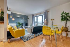 una sala da pranzo e un soggiorno con tavolo in vetro e sedie gialle di The Contractor City Spot with Parking a Derby