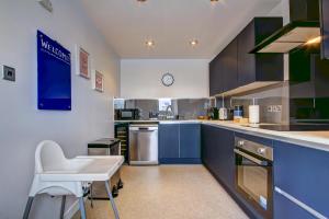 a large kitchen with blue cabinets and a white chair at River Ayr View-Coorie Doon Stays in Ayr