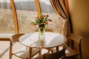 a vase of flowers on a table in front of a window at Glamp Zielone Skałki in Kluszkowce