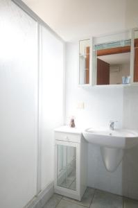 W białej łazience znajduje się umywalka i lustro. w obiekcie Residence Loggetta Margherita w mieście San Vincenzo