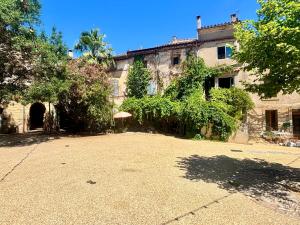 an old house with a large courtyard in front of it at Logement entier dans les Corbières in Coustouge