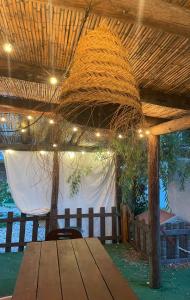 a wooden table under a straw roof with a chair at Casa na Quinta in Elvas