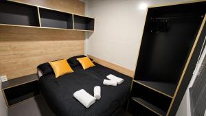 a small bedroom with a black bed with yellow pillows at Relax Tiny House Ljubljana in Ljubljana +19 photos
