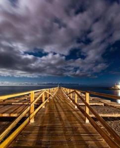 a wooden boardwalk leading to the ocean under a cloudy sky at Casa Luz in Playa Santiago in Alajeró
