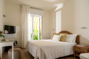 a white bedroom with a bed and a window at Villa Arizona in Milano Marittima