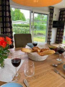 a table with a basket of bread and glasses of wine at Ferienhaus 4 Personen bei Giethoorn, Chalet in Holland in De Bult +10 photos