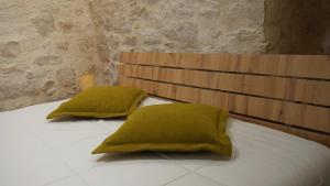 twee groene kussens bovenop een bed bij Laura stone room in Corato