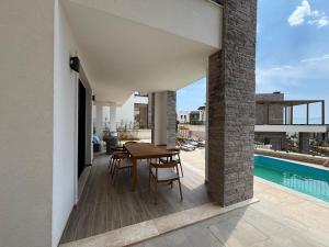 a patio with a table and chairs and a swimming pool at Turquoise Poolside Thymus Resort 34-1 in Dhërmi
