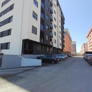 a parking lot with cars parked next to a tall building at Apartman 51 Sarajevo in Donje Mladice