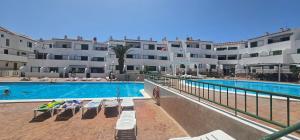 a swimming pool with lounge chairs in front of a building at Alondras Luxury Paradise fully renovated in Arona
