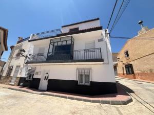 ein weißes Gebäude mit einem Balkon an einer Straße in der Unterkunft Casa Milamaria in María
