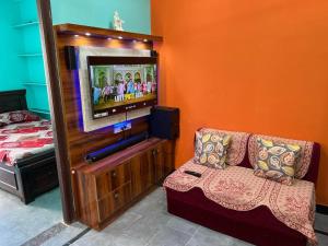a living room with a couch and a television at Brand New 1BHK Ganesh Nivas 2nd Floor in Secunderabad