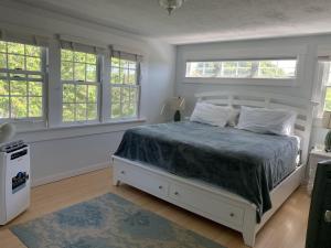 a bedroom with a white bed with windows at Katama Family Fun in Edgartown