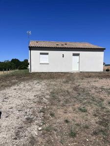 a white building with two windows in a field at Maison au calme in Douzillac