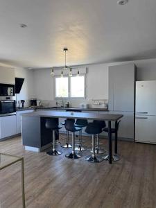 a kitchen with a large table and bar stools at Maison au calme in Douzillac