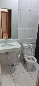 a white bathroom with a sink and a toilet at Casa Amarela in Itapetininga