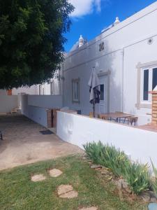 Casa blanca con mesa y sombrilla en Cosy Country House, en Cerro da Cova