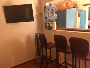 a bar with three chairs and a television at Suites colibri in San Miguel de Allende