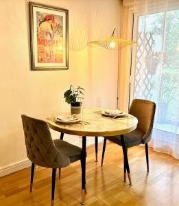 a dining room table with two chairs and a potted plant at L'écrin du 12- Studio élégant sur jardin avec parking in Paris +7 photos