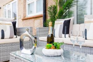 Una botella de champán sobre una mesa de cristal en un patio. en 5 Bedroom House , Free Parking , Pool Table , Arcade Machine , Garden , Sleeps 9 , Offers , Ideal For Contractors , Families , Long Term Stays, en Streatham Hill